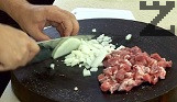 В сгорещена мазнина поставяме нарязаните на кубчета лук и чушка. Пържат се за минута. Осоляваме пържолите и ги нарязваме на малки късчета. Добавяме в тигана.