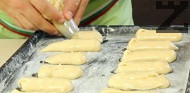 Introduce la masa en una manga pastelera y forma tiras alargadas para los éclairs sobre una bandeja engrasada y forrada con papel de horno. Hornea en el horno precalentado a 190 °C durante unos 22–25 minutos, hasta que estén dorados. Apaga el horno, deja la puerta entreabierta y mantén los éclairs d