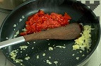 Запържваме за кратко наситнените лук и чесън в сгорещения зехтин. Нарязваме на кубчета обелените и почистени от семето печена чушка и домат. Запържваме всички продукти в един съд, но без да ги смесваме. Поръсваме със сол и черен пипер.