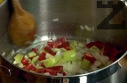 Запържваме в сгорещена мазнина за кратко нарязания на кубчета лук. Добавяме кубчетата от чушки и дребни парченца пресен лук.