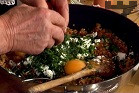 След като сместа се охлади, прибавяме натрошеното сирене, наситнените пресни подправки,черния пипер и яйцата. Разбъркваме добре.
