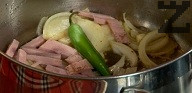 В същата мазнина запържваме нарязаните на кубчета лук, чесън, люта чушка и шунка. Поръсваме с черен пипер, наливаме около 150мл вода. Добавяме разтвореното в 200 мл вода доматено пюре.