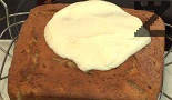 Нанасяме обилно върху сладкиша, отгоре редим колелцата банан, поръсваме с ядки.