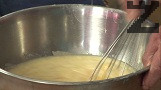 Прехвърляме към останалите продукти, разбъркваме добре, добавяме разтопената свинска мас. Прибавяме на части брашното, като разбъркваме непрекъснато. Замесваме меко тесто, поставяме го в намаслена тава.