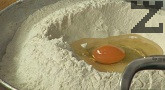 Пресяваме брашното, посоляваме, поливаме с олио и оцет, добавяме яйцето. Наливаме 300 мл хладка вода, замесваме тесто.
