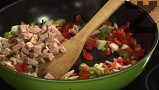 Режем бекона на малки кубчета, прехвърляме го към останалите зеленчуци. Продължаваме да запържваме на по-силен огън. Наливаме 1 к.ч. от водата, в която е варен фасула. Задушаваме, докато продуктите омекнат. Поръсваме със сол и кимион, разбъркваме. Прибавяме и нарязания бекон.