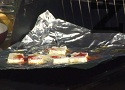 Върху скарата поставяме алуминиево фолио, с лъскавата страна надолу. Поливаме с мазнина, отгоре подреждаме филийките твърдо сирене. Поръсваме с червен пипер, поливаме със струйка зехтин.