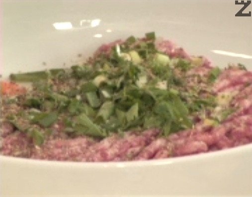 Picamos finamente la cebolleta y el perejil. Los añadimos a la carne picada junto con el huevo y las especias. Amasamos bien hasta integrar todos los ingredientes. 