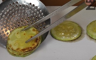 Тиквичката се нарязва на колелца, запържва се за минута и слага върху салфетка. 