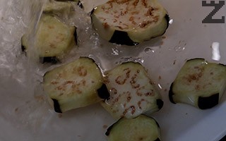 Патладжанът се почиства, измива и нарязва на колелца. Посолява се и се оставя за 30 минути, за да се отцеди горчивият сок. 