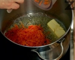 Морковът се настъргва на ренде. В тенджера се стопява масло и моркова се задушава под капак за две минути. 