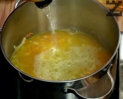 Нарязва се на дребно лук и добавя при моркова. Задушава се за минута. Налива се един и половина литра гореща вода. 